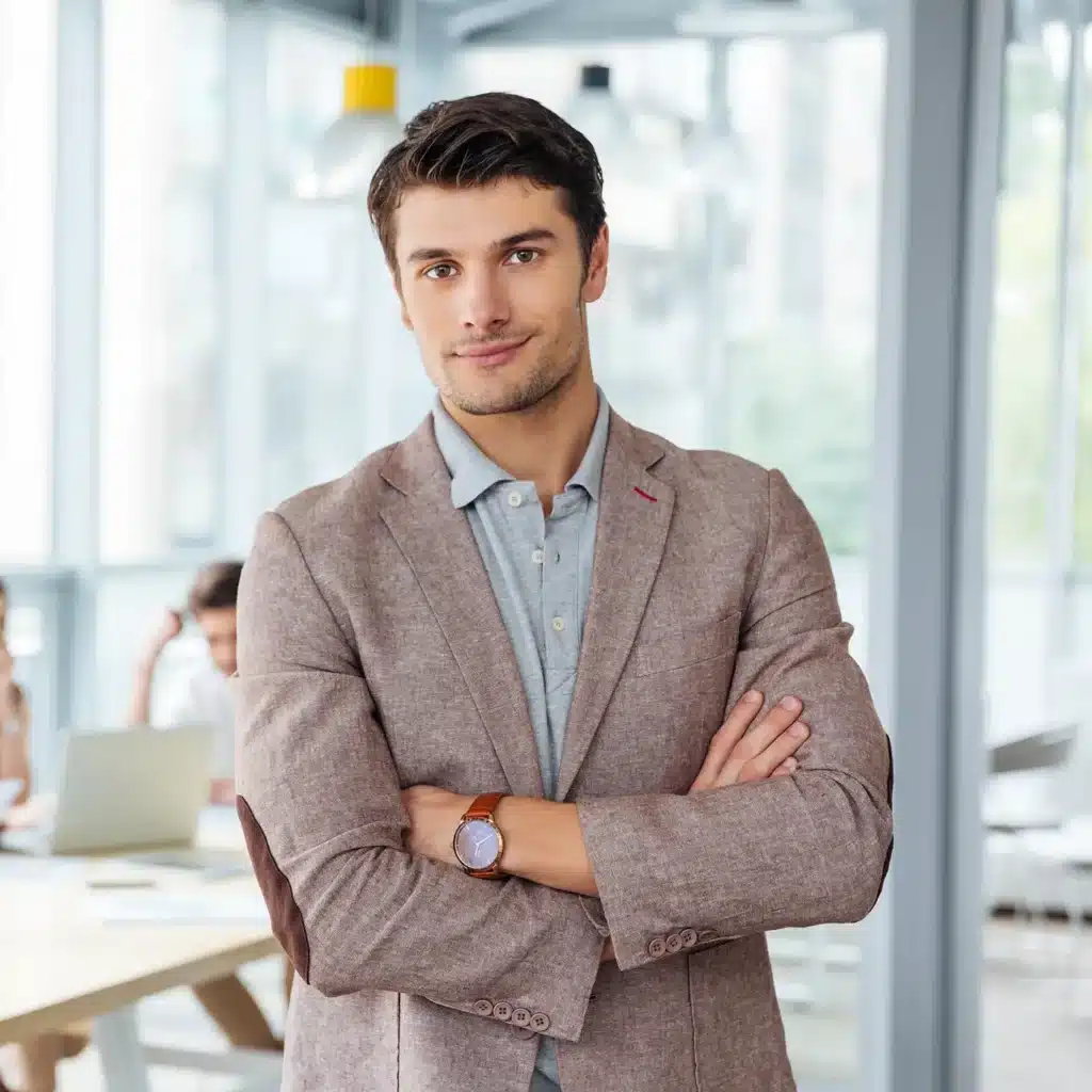 Successful businessman standing with arms crossed in office